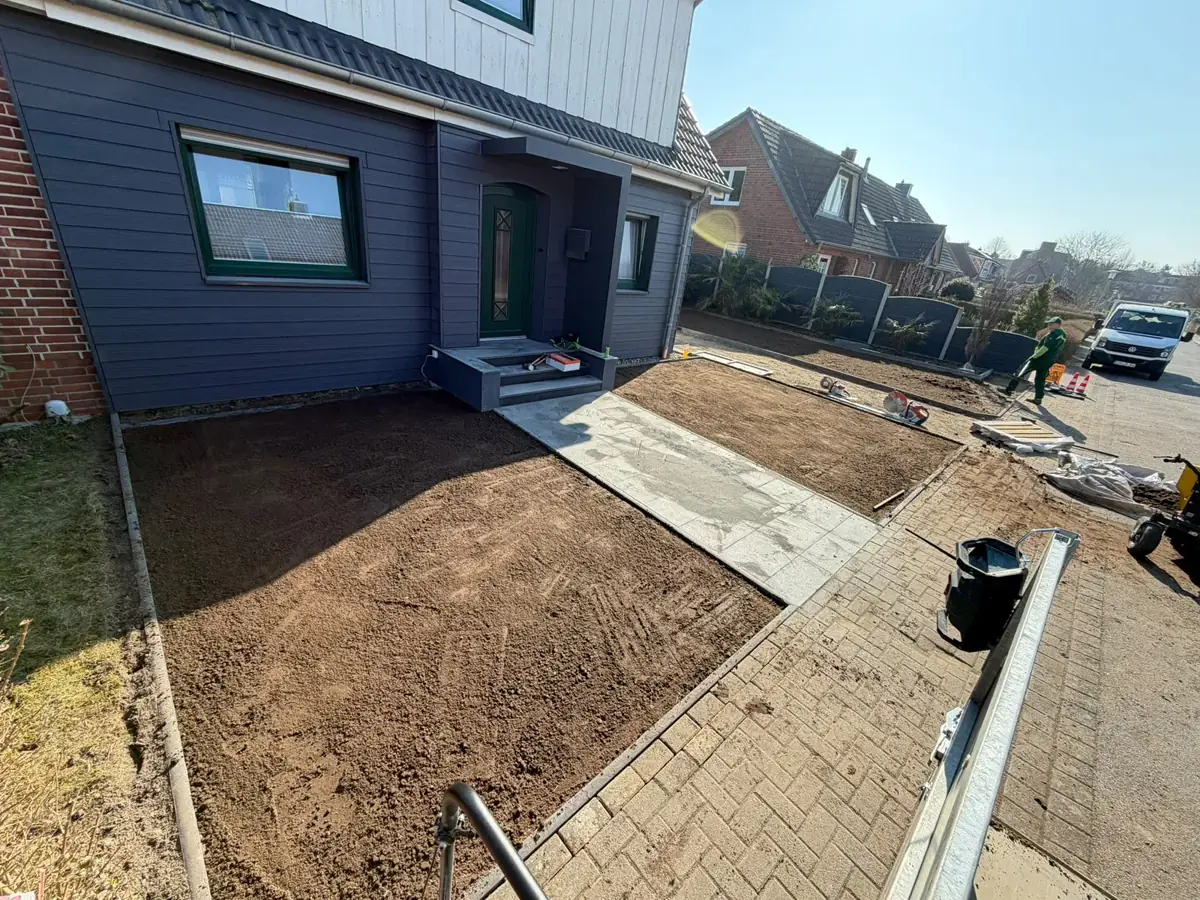 Derselbe Vorgarten vorher: frisch aufgetragener Mutterboden neben dem neuen Plattenweg