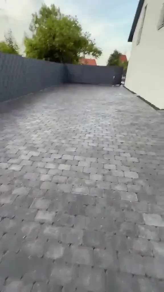 Fertig gepflasterter Hof mit neuem anthrazitfarbenem Sichtschutzzaun