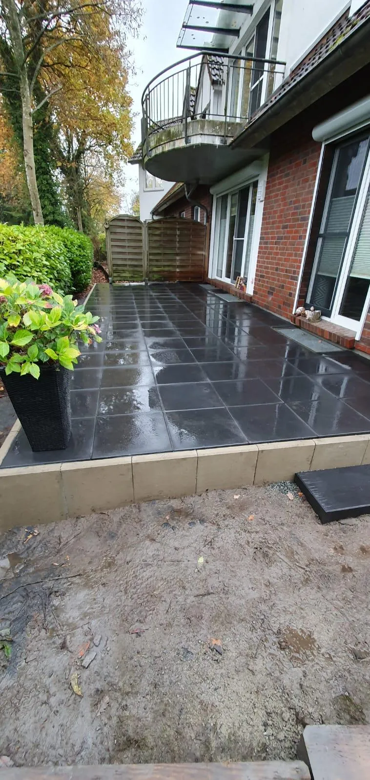 Fertige Terrasse mit großen Anthrazit-Platten und stabiler Betoneinfassung